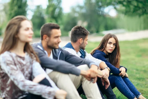 Jongeren zitten op groen gras — Stockfoto