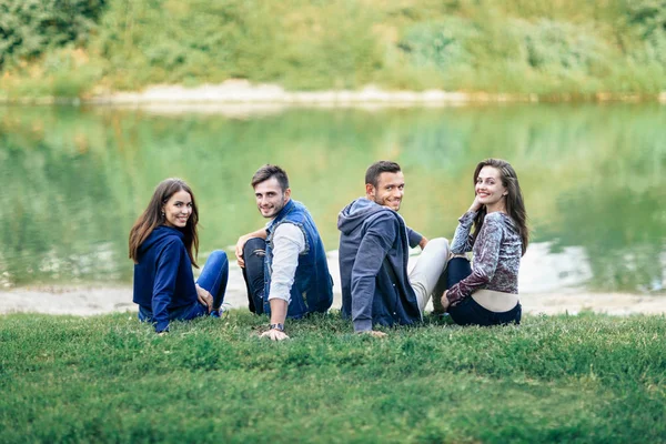 Молодые люди сидят на зеленой траве — стоковое фото
