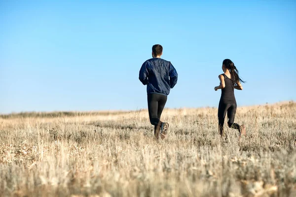 Młoda para biegająca po polu — Zdjęcie stockowe