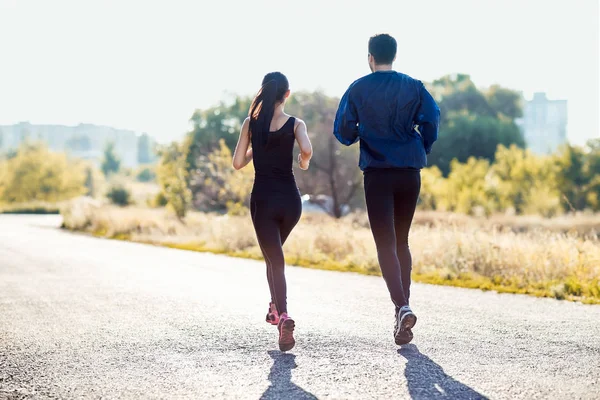 Pareja joven corriendo por la carretera — Foto de Stock