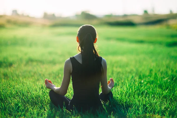 Genç kadın çimenlerin üzerinde meditasyon — Stok fotoğraf