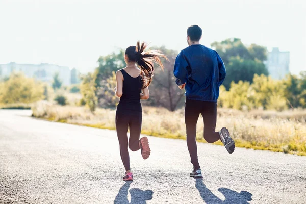 Pareja joven corriendo por la carretera — Foto de Stock