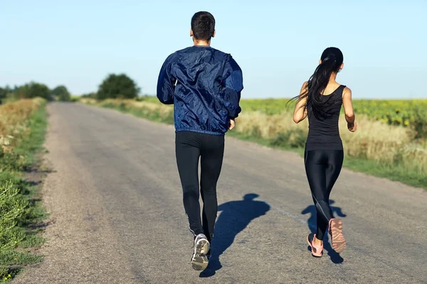 Young couple running on road — Stock Photo, Image