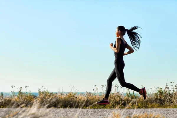 Jeune femme courant le long de la route — Photo