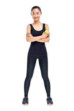 Güvenle ayakta ve yeşil elma beyaz arka plan üzerinde izole tutmak gülümseyen genç Asyalı atlet