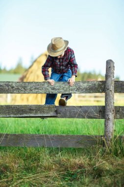 Küçük kovboy tahta çitin üzerinden, açık tırmanıyor. Çocuk açık havada haystacks zemin ile ahşap çit üzerinde çalış. Küçük Gezgin yeni fırsatlar araştırıyor