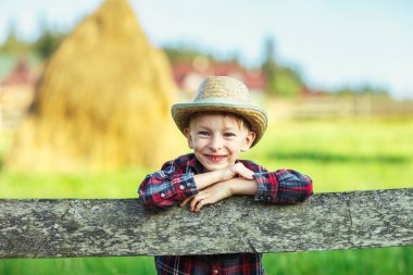 Yakın şapkalı mutlu küçük çocuk portresi ahşap çit eğildi. Mutlu çocukluk kavramı. Tatil