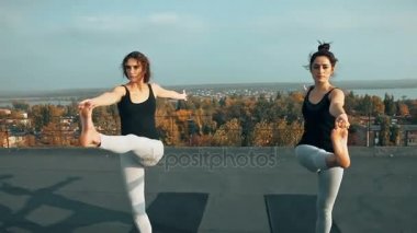 Yoga asana çatıda, açık havada sabah pratik iki güzel kadın. Ayakta poz dengesini koruyarak. Asana hatha yoga denge ve konsantrasyon. Ortak yoga