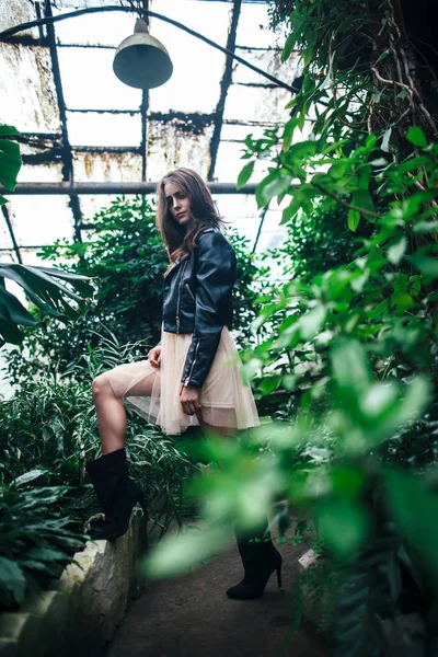 Full Length portrait of trendy hipster girl posing in garden greenhouse background. Urban Fashion Concept