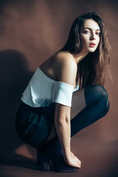 Junge Frau Posiert Auf Braunem Hintergrund Sitzend Der Hocke — Stockfoto