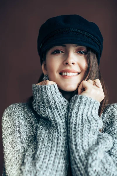 茶色の背景に暖かいウールのセーターに包まれた若い女性の肖像画 — ストック写真
