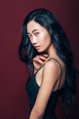 Studio kahverengi zemin üzerinde poz siyah elbiseli güzel Asyalı kadın. Güzel moda model portre