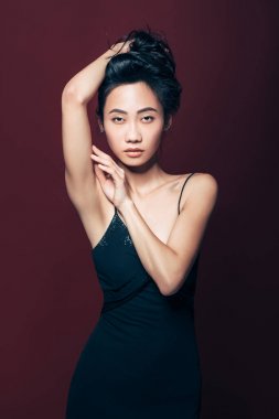 Studio kahverengi zemin üzerinde poz siyah elbiseli güzel Asyalı kadın. Güzel moda model portre
