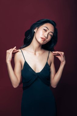Studio kahverengi zemin üzerinde poz siyah elbiseli güzel Asyalı kadın. Güzel moda model portre