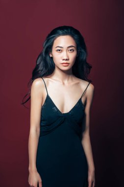 Studio kahverengi zemin üzerinde poz siyah elbiseli güzel Asyalı kadın. Güzel moda model portre