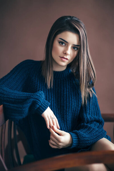 Красивая молодая женщина отдыхает на диване на коричневом фоне. Модный портрет
. 