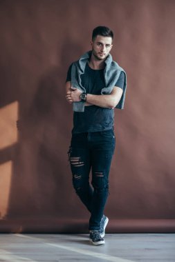 Çapraz kolları üzerinde kahverengi zemin poz olan seksi kaslı adam portresi tam uzunlukta