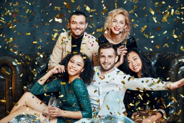 Çeşitli gülen arkadaşlar konfeti yağmuru altında eğleniyor ve eğleniyorlar.