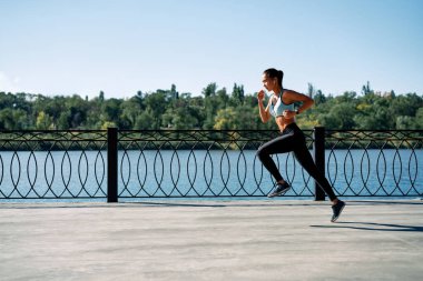 Nehirden dışarı koşan sportif bir kadın. Spor giyim sektöründe güzel bir kadın. Dinamik hareket   