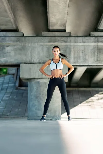 Beautiful confident woman in sportswear posing outdoors. Beauty and sport concept