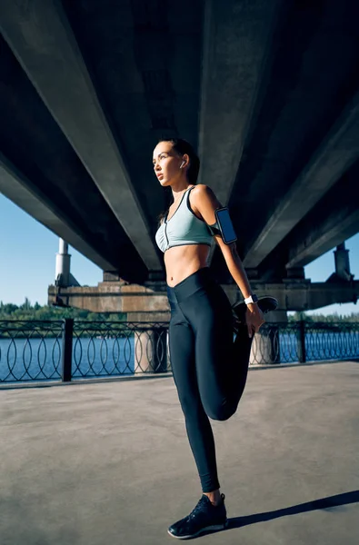 身材苗条的女子跑步者在运动前伸展腿以进行热身 城市锻炼和跑步概念 — 图库照片