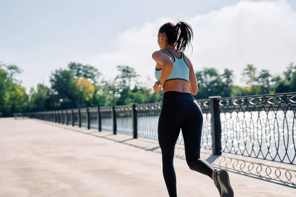 一个健康的女人从河边跑到户外的背景 穿着运动服在户外慢跑的漂亮女人 动态运动 — 图库照片