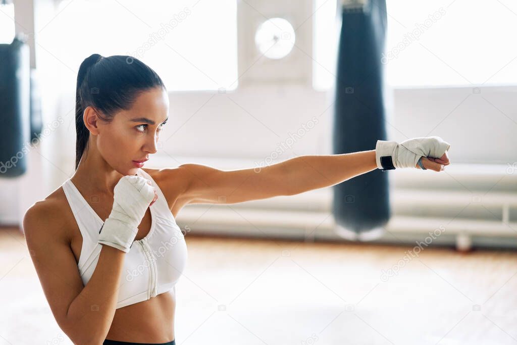 Female boxer practicing her punches at a boxing studio.  Athletic woman making direct hit. Sport concept                          
