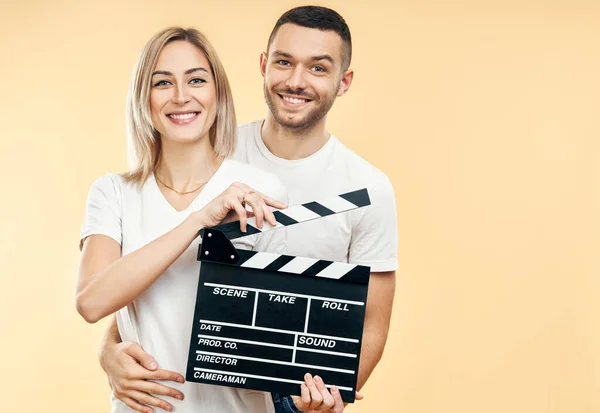 映画のクラッパーボードと若い幸せなカップル 男は映画のクラッパーボードを持つ女性を抱いている 映画学の概念 — ストック写真