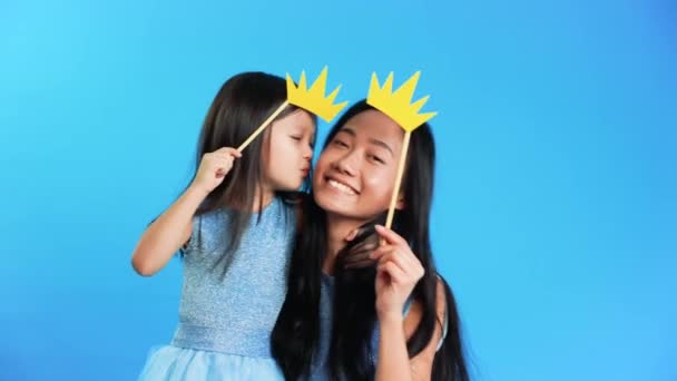 Mother and cute little daughter with a paper crown on stick kiss each other and have fun together — Stock Video