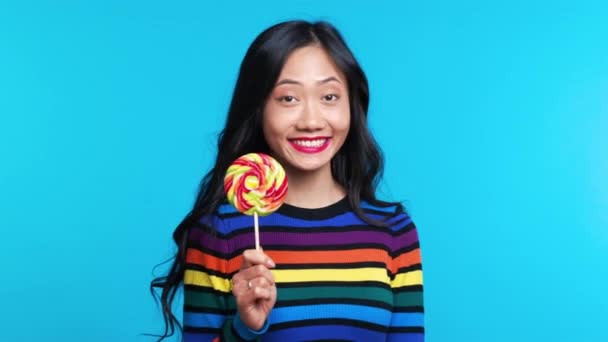 Mujer hermosa feliz con piruleta colorido aislado sobre fondo azul — Vídeos de Stock