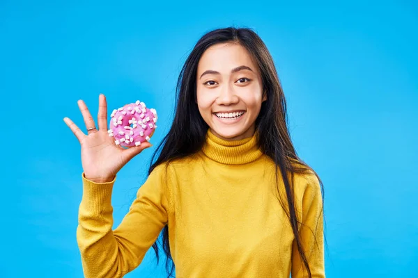 Mulher feliz atraente segurando saboroso donut sobre fundo azul — Fotografia de Stock