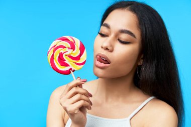 Genç, güzel siyah kadın renkli lolipop yalıyor.