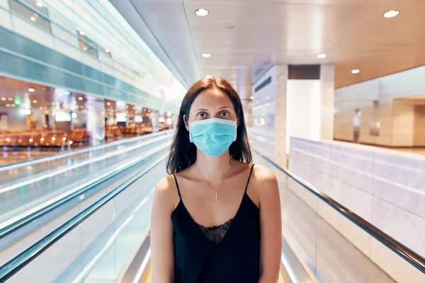 Vrouw in bescherming gezichtsmasker poseren in modern winkelcentrum of luchthaven — Stockfoto