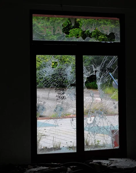 An old window with glass shattered and smashed in an abandoned building