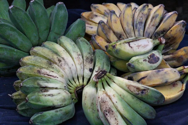 青い布の上に広げて新鮮な収穫の緑と黄色のバナナ — ストック写真