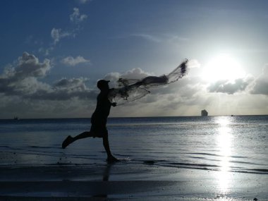 Saipan, Cnmi- Aralık 2018: Alacakaranlıkta geleneksel balık ağı atan tanınmayan bir balıkçının silueti