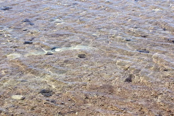 Tropik bir adada sığ bir plaj üzerinde akan dalgalar oluşturan kristal berraklığında sular