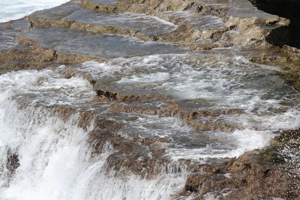 Denizde keskin mercanlar ve kaya platformları üzerinde köpüklü suların Cascades