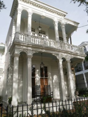 New Orleans, Louisiana tarihi Charles Avenue boyunca balkonda sallanan sandalye ile güzel bir beyaz sömürge evi.