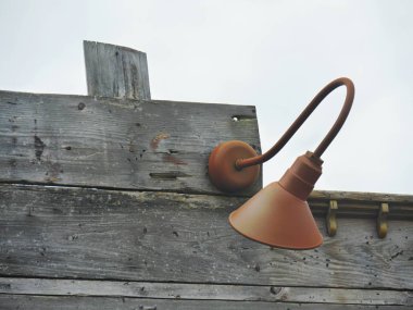 Ahşap bir duvara açık havada monte edilmiş antik aparat lambası