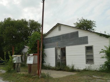 Wynnewood, Oklahoma, Wynnewood 'daki terk edilmiş bir binanın önünde iki benzin pompası olan terk edilmiş bir benzin istasyonu. Fotoğraf Eylül 2015 'te çekildi. 