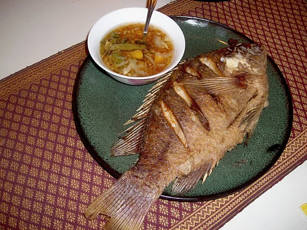 Kızarmış tilapia balık küçük bir yuvarlak tabakta soğan, sarımsak, sirke ve diğer baharatlar baharatlı daldırma ile servis