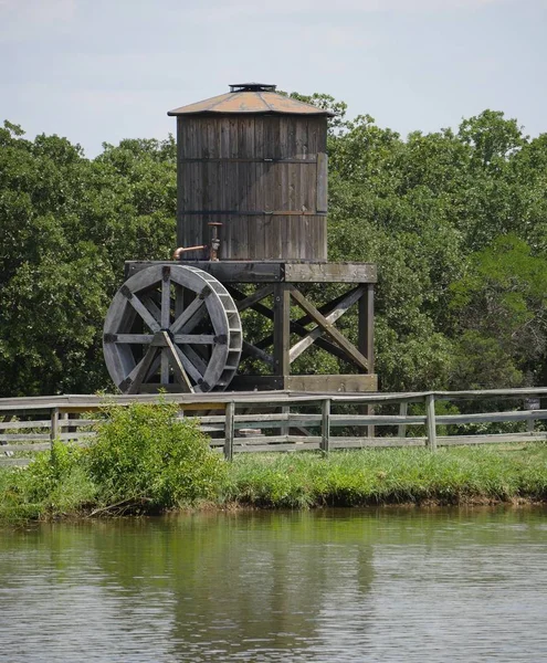 Old wooden water wheel with wooden tank by a pond side