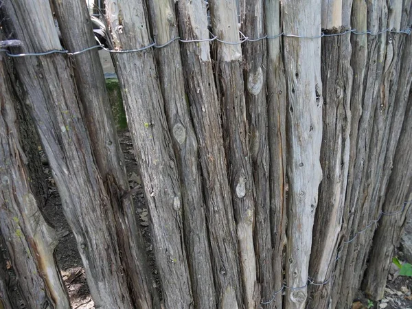 Rough round wooden fence posts tied together by a piece of wire