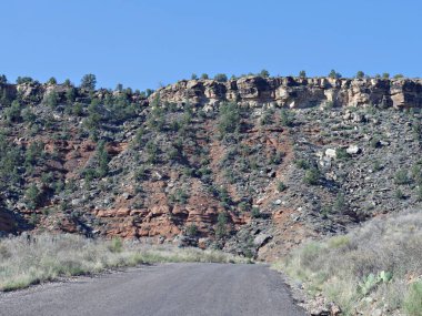 Utah 'taki Zion Ulusal Parkı' nın birkaç mil uzağında yüksek kızıl kayalıkların ve taş oluşumlarının etrafında dönen engebeli bir yol..
