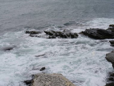 Kayalık kıyılara yuvarlanan köpüklü dalgaların aşağı doğru görüntüsü