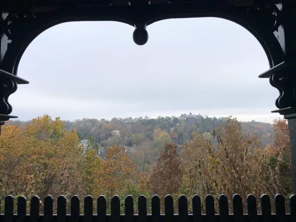 Framed view of colorful trees in autumn, with the Crescent Hotel & Spa in the distance at Eureka Springs, Arkansas.