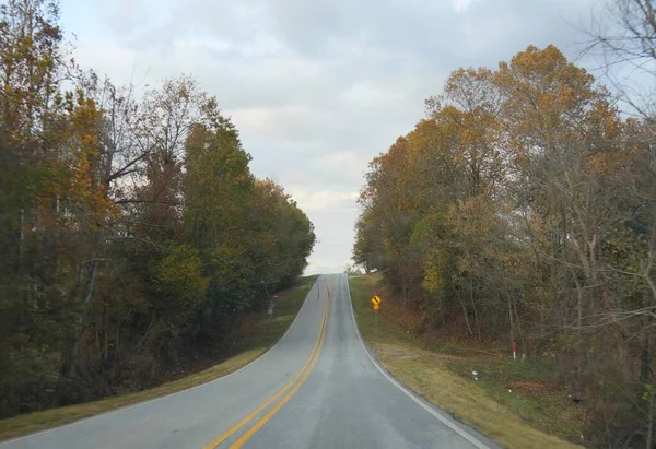 秋の間に両側にカラフルな木々と広い傾斜道路 — ストック写真