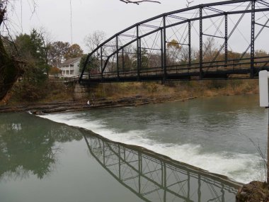 Arkansas Benton County 'de soğuk bir sonbahar sabahı War Eagle nehrinin sularına yansıyan eski tarihi köprü.