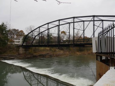 Arkansas Benton County 'de soğuk bir sonbahar sabahı War Eagle nehrinin sularına yansıyan tahta köprü..